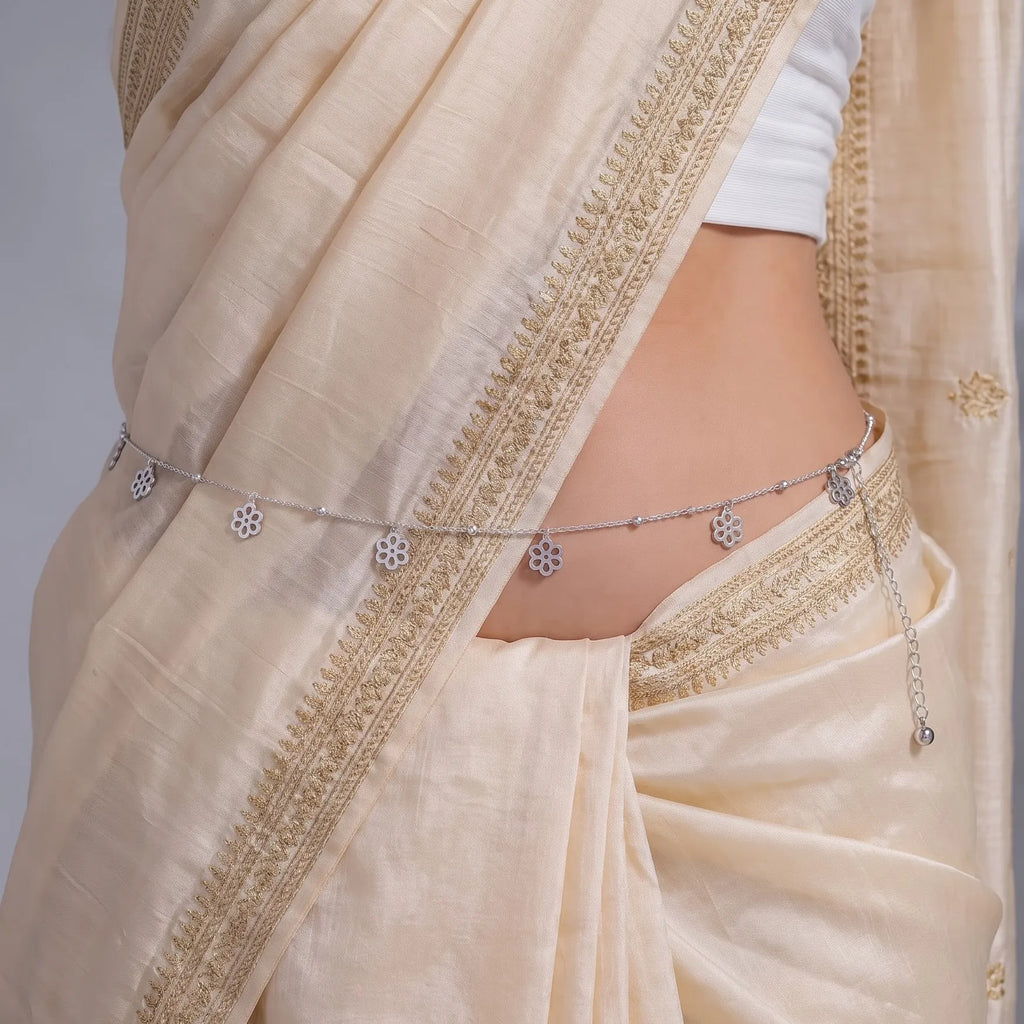 Marvel Silver Floral Charm Adjustable Silver Kamarbandh Worn by Woman with Cream and Gold Embroidered Saree Featuring Delicate Flower Charms and Polished Silver Beads