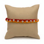 Marvel Silver floral motif yellow red rakhi with multiple silver-tone decorative charms