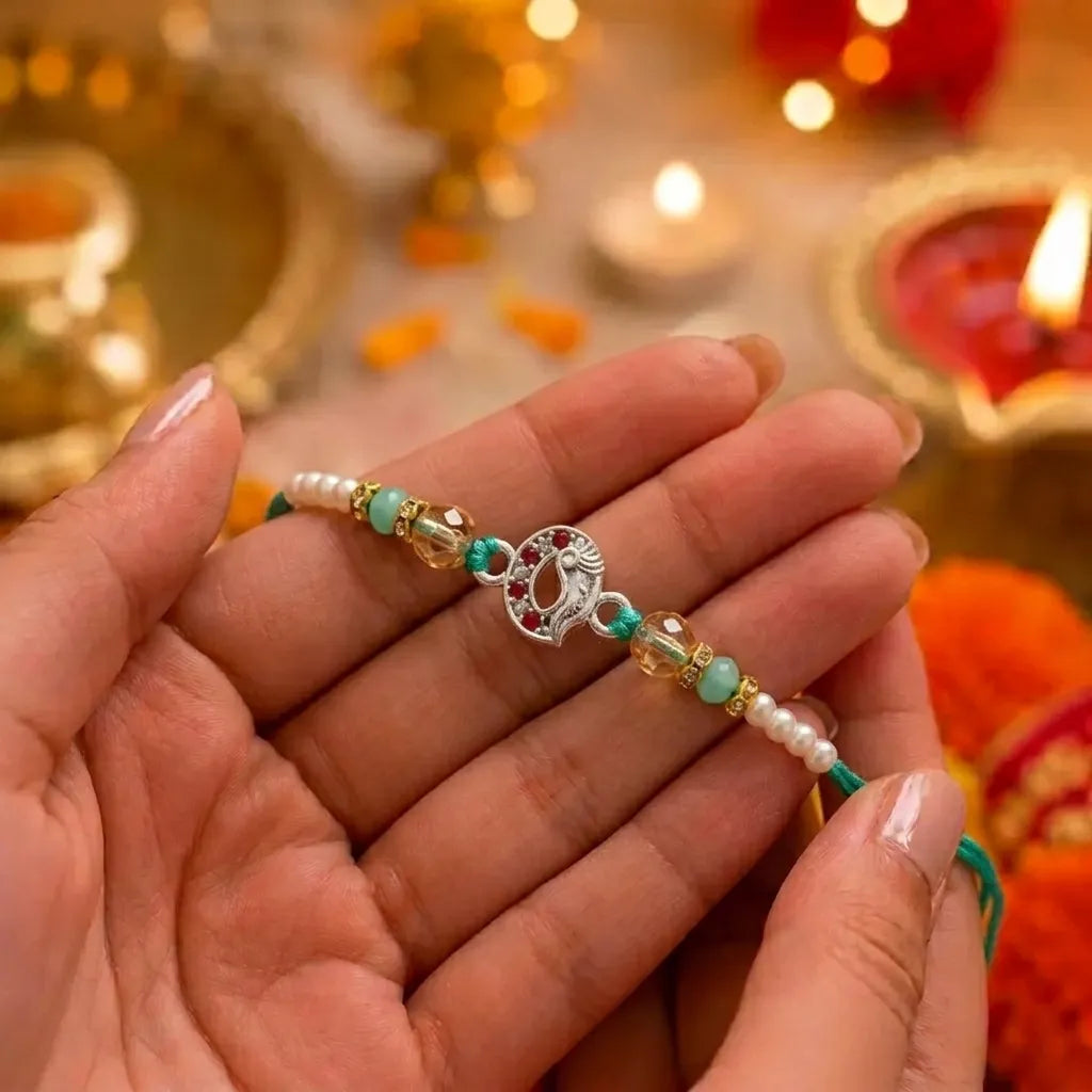 Marvel Silver Ganesh Silver Rakhi with Green Crystal Beads, White Pearl Beads, Golden Accent Beads and Red Green CZ Stones for Raksha Bandhan