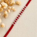 Marvel Silver red thread rakhi with polished silver-tone repeating bead cluster pattern