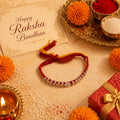 Marvel Silver Silver Bead Flower Designer Rakhi featuring a handcrafted floral silver bead centerpiece with red and yellow braided thread for Raksha Bandhan.