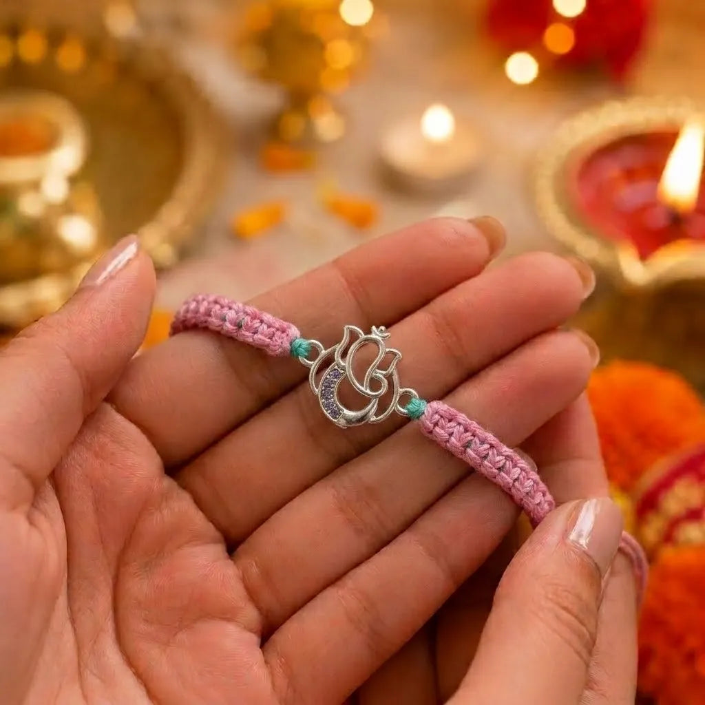 Marvel Silver Designer Ganesh Rakhi with silver-finish Lord Ganesha charm, pink braided thread, and sparkling stone detailing for Raksha Bandhan.