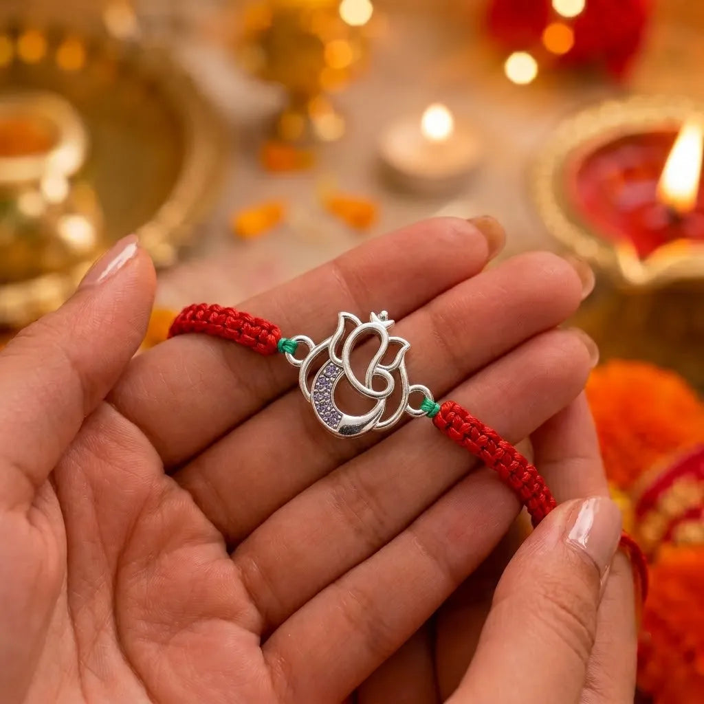 Marvel Silver Designer Ganesh Rakhi with silver-finish Lord Ganesha charm, pink braided thread, and sparkling stone detailing for Raksha Bandhan.