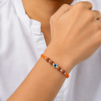 Marvel Silver Evil Eye Rudraksha Rakhi with polished silver beads on a saffron and red braided thread