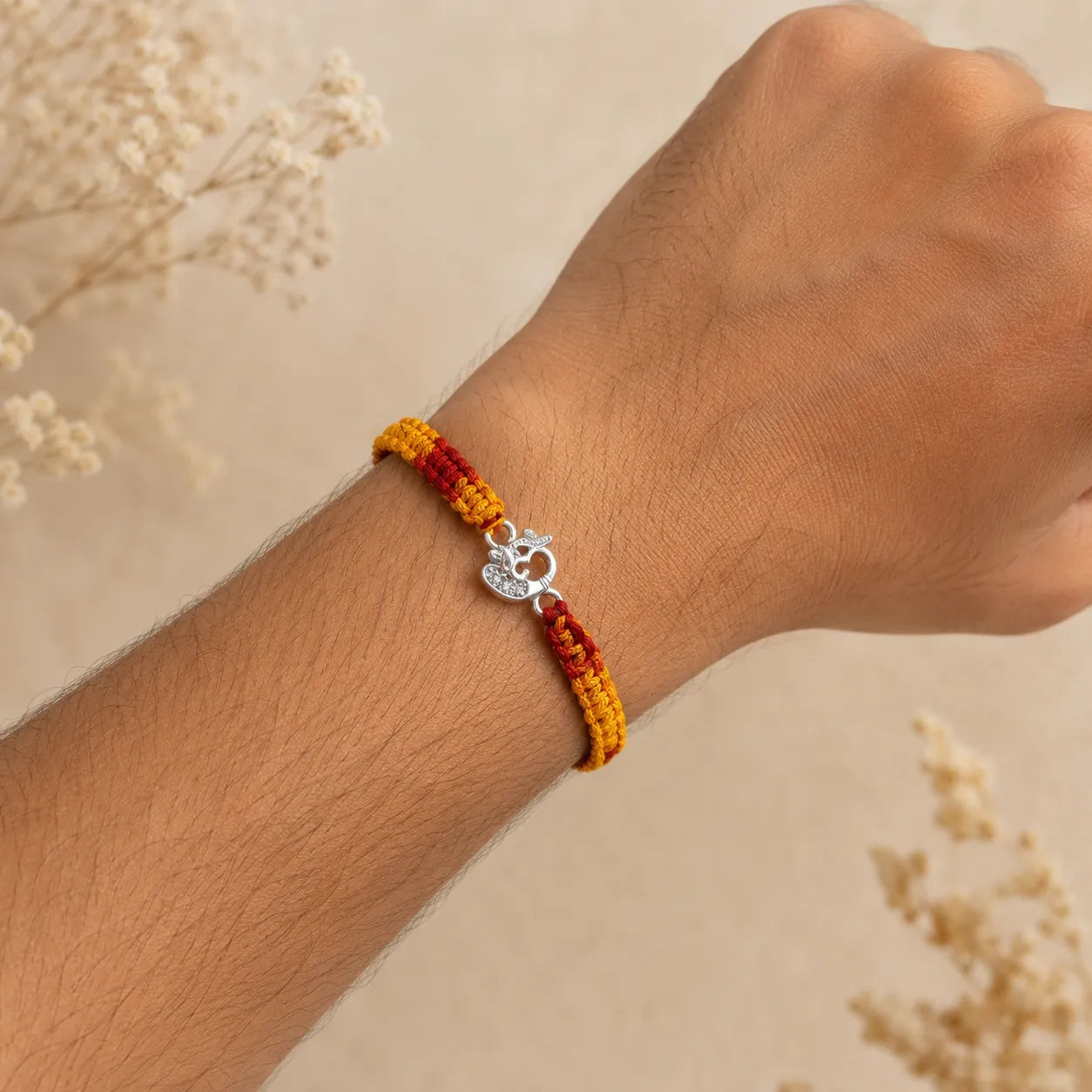 Marvel Silver Om design rakhi for brother with yellow red braided thread and silver-tone stone-studded charm