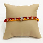 Marvel Silver Om Designer Rakhi featuring a silver-finish Om charm with crystal beads on a handcrafted red and yellow thread for Raksha Bandhan.