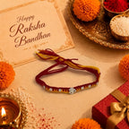 Marvel Silver Om Designer Rakhi featuring a silver-finish Om charm with crystal beads on a handcrafted red and yellow thread for Raksha Bandhan.