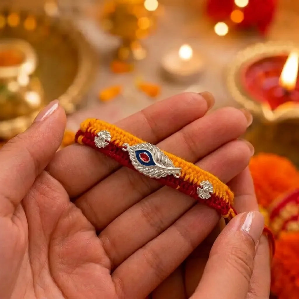 Marvel Silver designer silver peacock feather rakhi with red stone centerpiece and handcrafted yellow and red cotton thread for Raksha Bandhan.