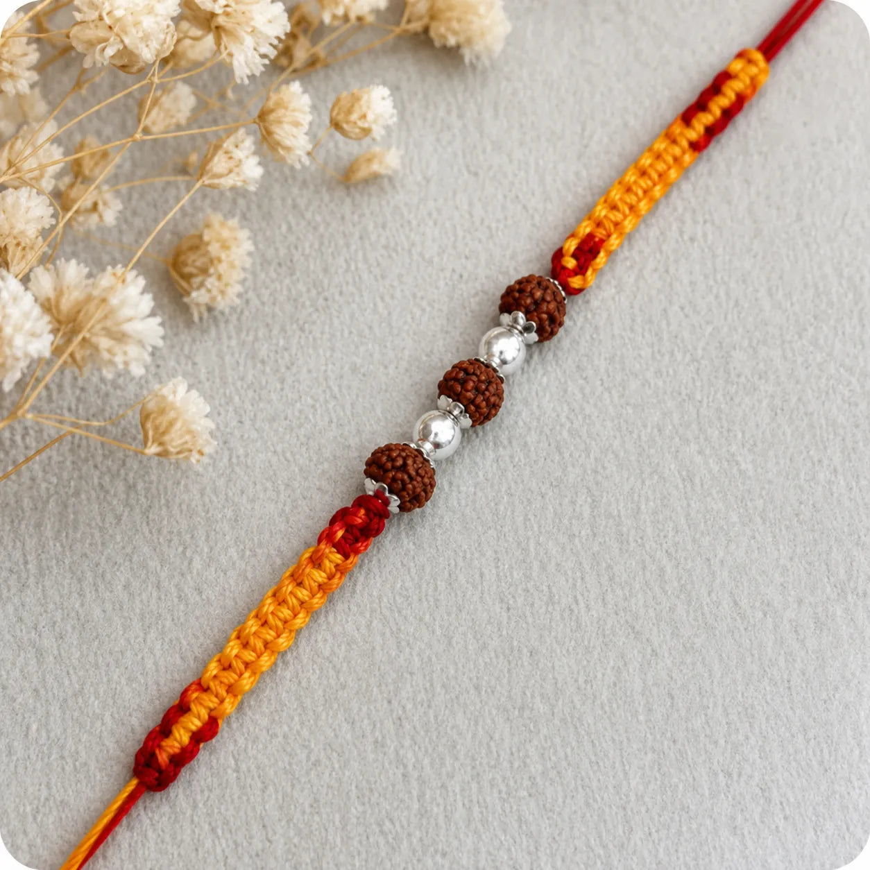 Marvel Silver Rudraksha bead rakhi with polished silver beads on a saffron and red braided thread