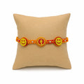 Marvel Silver Smiley Face Designer Rakhi with two smiley charms, center letter charm, silver-tone bead accents, and orange-red braided thread for Raksha Bandhan.