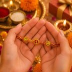 Marvel Silver Smiley Face Designer Rakhi with two smiley charms, center letter charm, silver-tone bead accents, and orange-red braided thread for Raksha Bandhan.