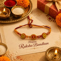 Marvel Silver Smiley Face Designer Rakhi with two smiley charms, center letter charm, silver-tone bead accents, and orange-red braided thread for Raksha Bandhan.