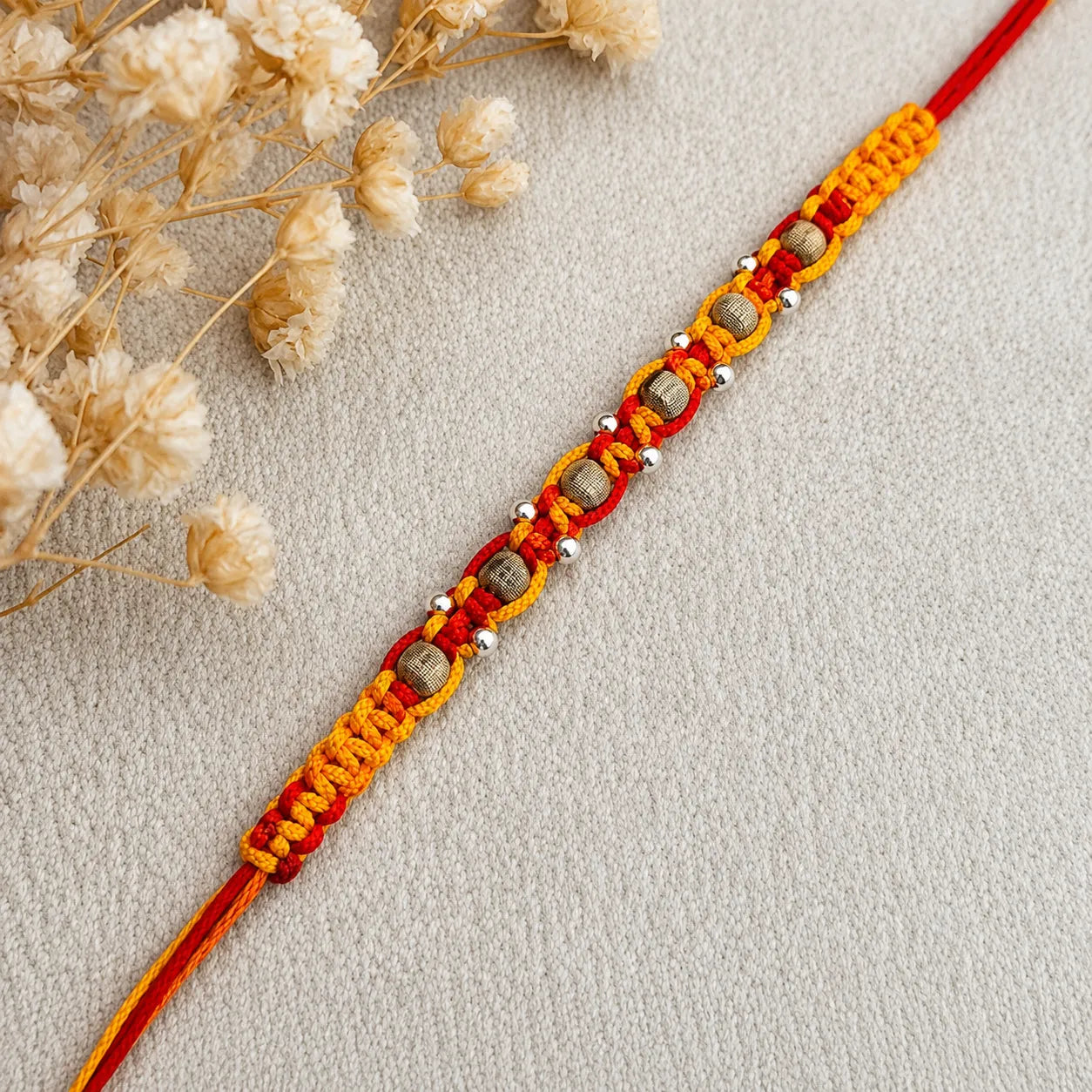 Marvel Silver wooden bead rakhi for brother with red yellow braided thread and silver-tone bead accents