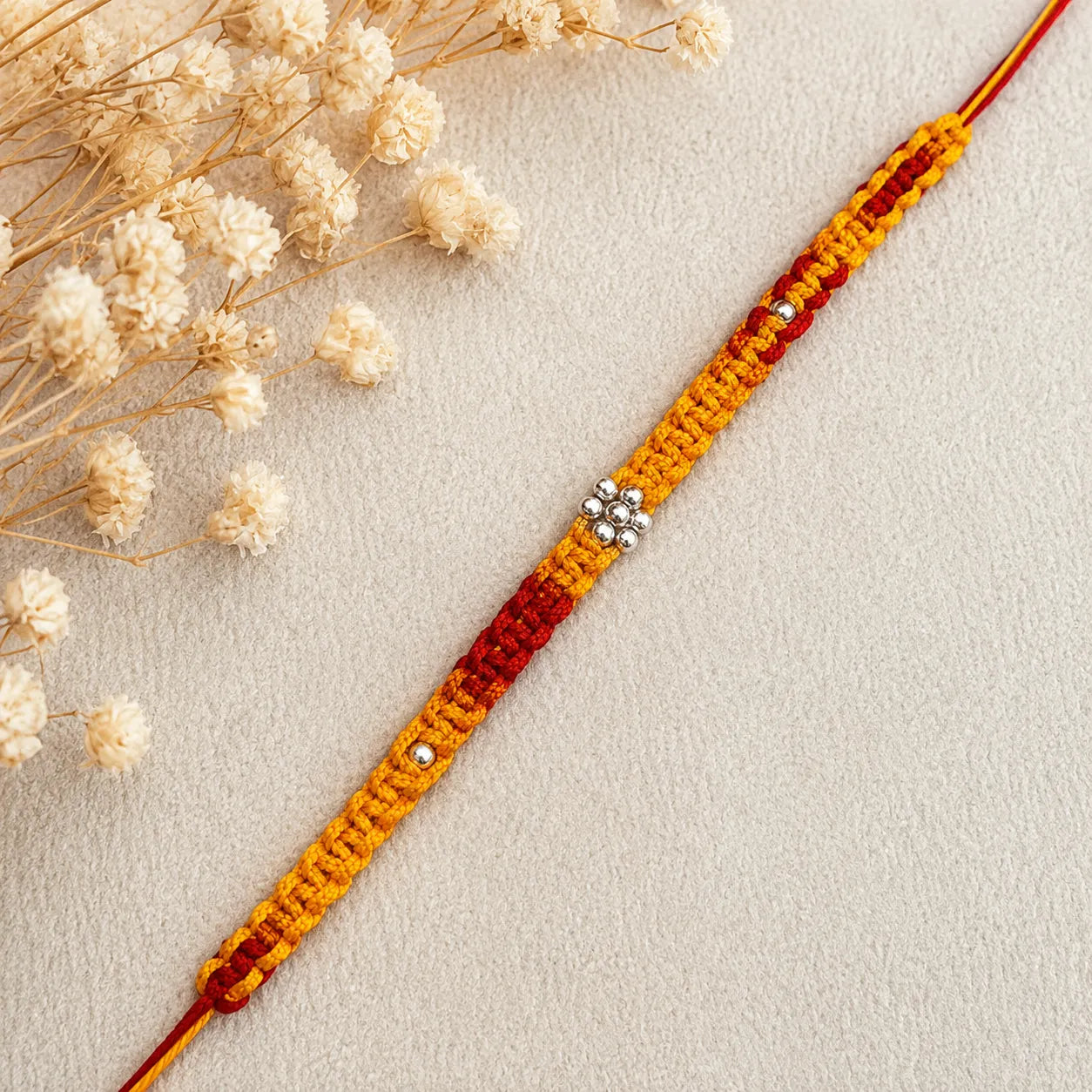 Marvel Silver yellow red floral bead rakhi for brother with polished silver-tone centre bead cluster