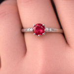 Red round solitaire with side stones