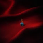 •A classic Evil Eye pendant with a blue and black concentric design, set in a gold-toned circular frame.