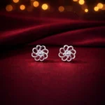 •Delicate silver flower-motif studs featuring open-work petals and a cluster of crystals at the center.