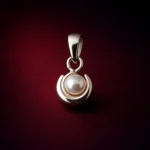 •A minimalist pearl pendant featuring a single white round pearl cradled within a polished, crescent-shaped silver-toned bale.