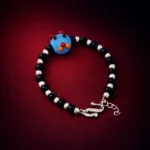 •A playful beaded bracelet for children, composed of black and silver-toned beads with a blue "cartoon face" centerpiece.