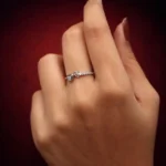 •A dainty silver promise ring with a thin, crystal-studded band and two interlocking heart motifs at the center.